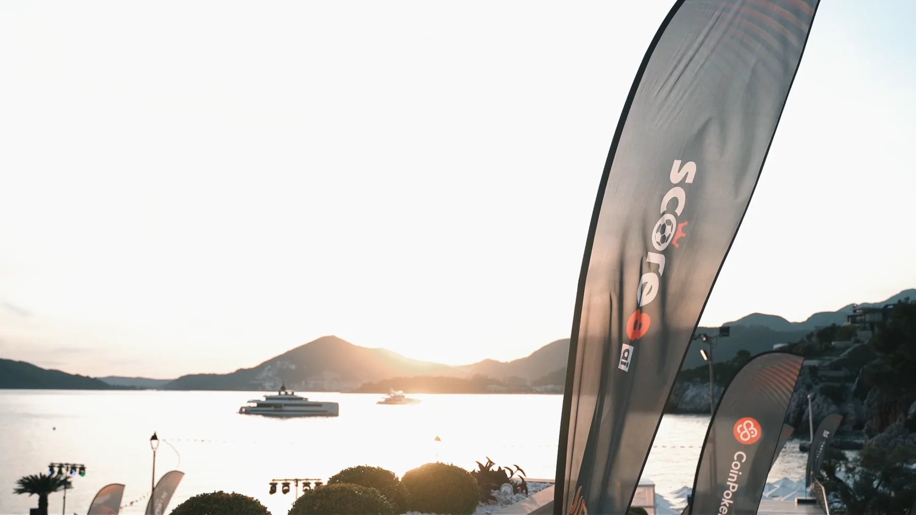 Score8 event flags overlooking a waterfront at sunset